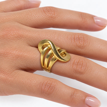Anello donna misura 18 dal design scultoreo dorato indossato al dito.
