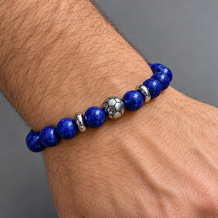 Bracciale elastico blu con piccolo pallone da calcio indossato attorno al polso.