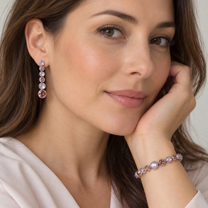 Set rosa e lilla indossato da una donna, con orecchino da circa4cm e bracciale al polso, simulazione visiva.