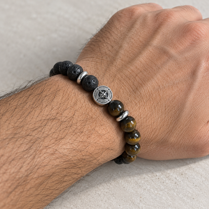 Bracciale elastico con rosa dei venti indossato al polso, con sfere nere e marrone-dorate.