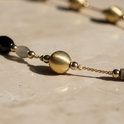 Dettaglio macro perle multicolore oro nero grigio e pietra dura collana lunga