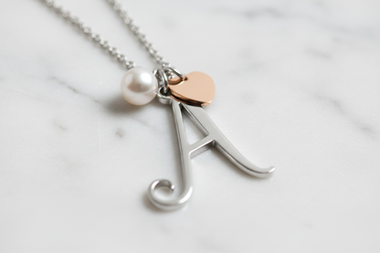 Dettaglio macro lettera iniziale con perla e cuore rosé - artigianalità premium