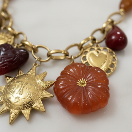 Dettaglio ciondoli resina: fiore arancio, cuore bordeaux, goccia ambra