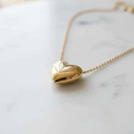 Dettaglio macro pendente cuore dorato con incisioni artigianali