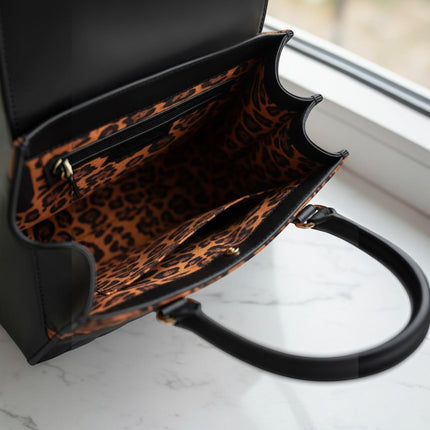 Tempo A Tempo black leather tote bag with leopard print lining and top handles.