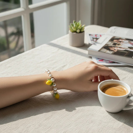 Bracciale Tempo A Tempo con perle bianche, perline dorate in acciaio e 3 charms limone gialli con foglie verdi. Chiusura ad aragosta.