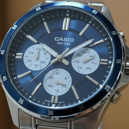 Tempo A Tempo Casio MTP-1374D watch with a blue multifunction dial, silver stainless steel case, and day-date display