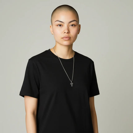 Modella indossa collana uomo 2Jewels in acciaio con ciondolo a croce su t-shirt nera, stile casual Tempo A Tempo