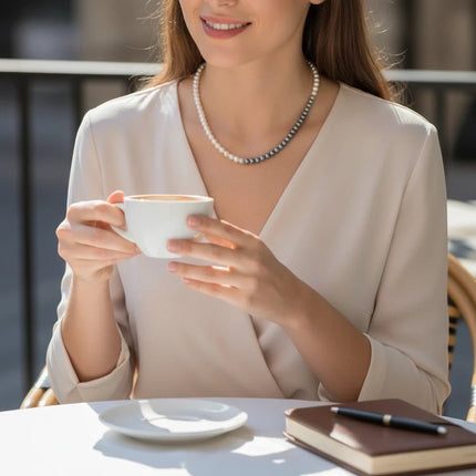 Tempo A Tempo Shelly glass pearl necklace with stainless steel clasp worn by a woman holding a coffee cup
