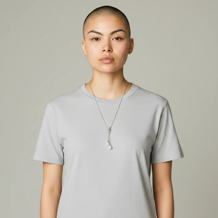 Tempo A Tempo long necklace with a heart pendant, sparkling zirconia, and white pearls on a model in a grey t-shirt