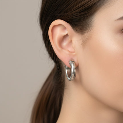 Orecchini a cerchio Tempo A Tempo in acciaio argentato con design tubolare scanalato indossati da una modella