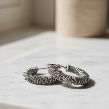 Orecchini a cerchio Tempo A Tempo in acciaio argentato con design a spirale intrecciata e finitura testurizzata.