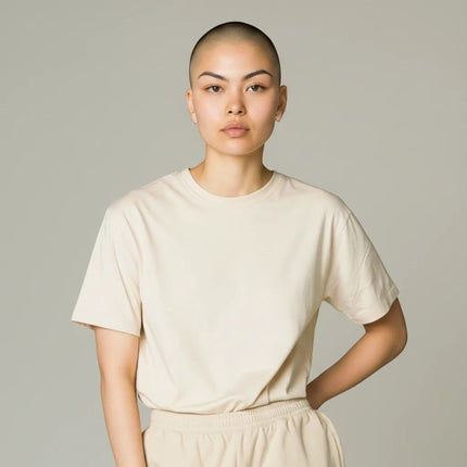 Modella con capelli rasati indossa orecchini a lobo Tempo A Tempo in acciaio dorato e resina marmorizzata beige