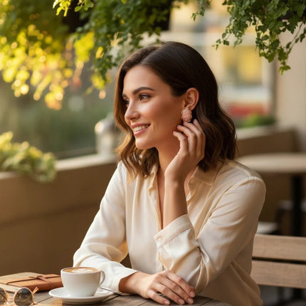 Donna sorridente indossa orecchini Tempo A Tempo in resina rosa cipria e acciaio dorato con forma organica al bar