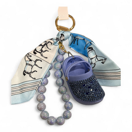 Portachiavi Tempo A Tempo con mini Crocs lilla, cristalli, foulard stampa cavalli e perle opalescenti su gancio oro.