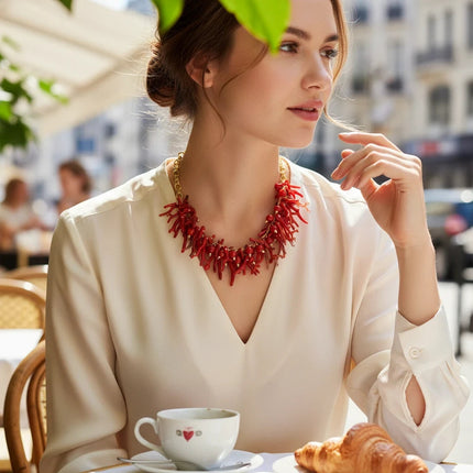 Tempo A Tempo ethnic style choker necklace with red synthetic coral branches and gold beads worn by a woman at a cafe