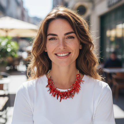 Tempo A Tempo ethnic style choker necklace with red synthetic coral branches and gold beads worn by a smiling woman