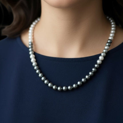 Tempo A Tempo Shelly necklace featuring a gradient of white to grey glass pearls worn by a woman in a navy top.