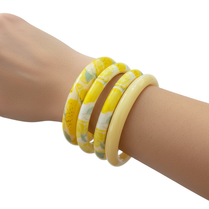 Tempo A Tempo set of 4 yellow resin bangles with lemon print and solid cream. Summer fashion accessory.